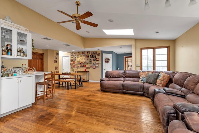 living area with a dry bar, ceiling fan, vaulted ceiling, light wood-style floors, and recessed lighting