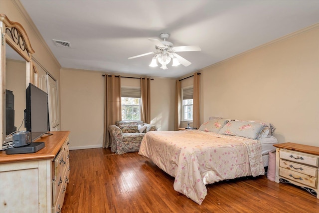 bedroom featuring crown molding, wood-type flooring, visible vents, a ceiling fan, and baseboards