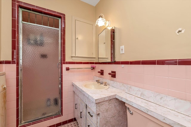 bathroom with a stall shower, wainscoting, vanity, and tile walls