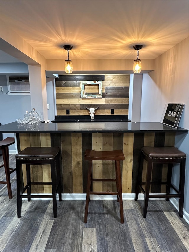 bar with dark wood-style flooring, a dry bar, a wall mounted AC, and pendant lighting