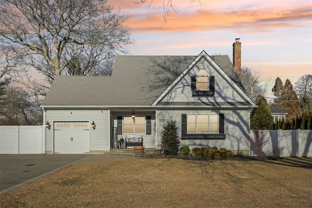 traditional home with a garage, fence, a chimney, and a lawn