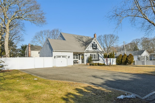 view of front of property featuring a chimney, fence, aphalt driveway, and a front yard