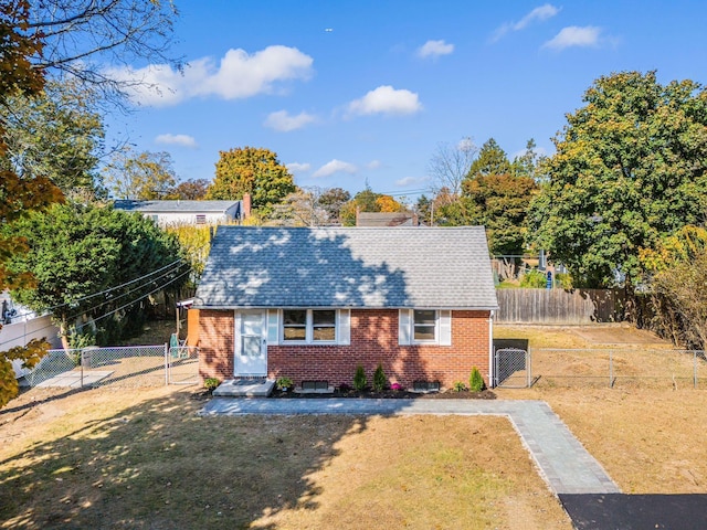 view of front of property with fence private yard, a gate, brick siding, and a front lawn