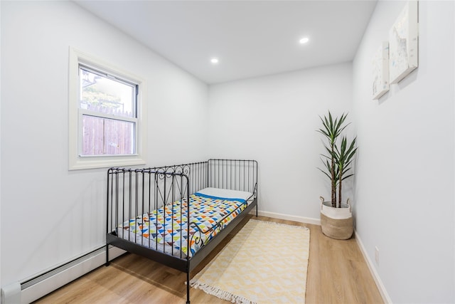 bedroom featuring baseboards, a baseboard heating unit, wood finished floors, and recessed lighting