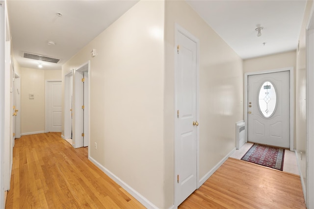 foyer entrance featuring baseboards, radiator, visible vents, and light wood-style floors