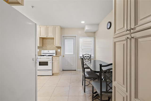 kitchen with white appliances, backsplash, cream cabinetry, and light countertops