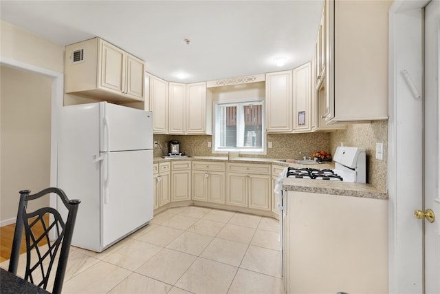 kitchen with white appliances, visible vents, light countertops, cream cabinetry, and backsplash