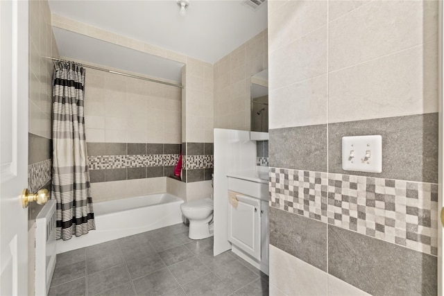 full bath with shower / tub combo with curtain, tile walls, toilet, vanity, and tile patterned floors