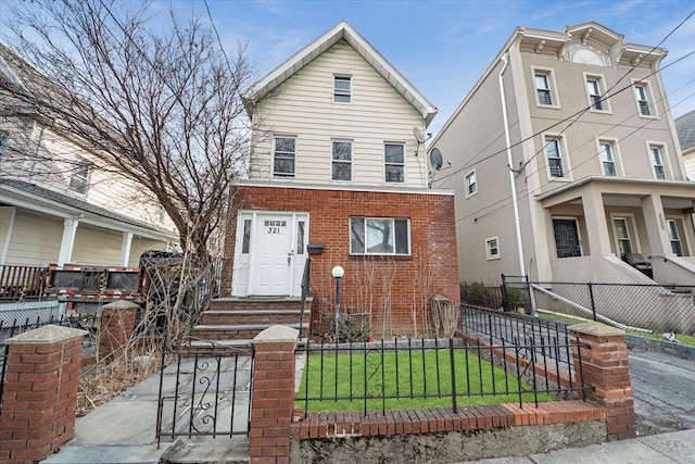 view of front of home with brick siding, a fenced front yard, and a front lawn