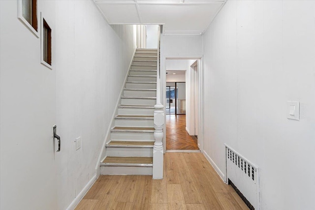 stairs with radiator, baseboards, and wood finished floors