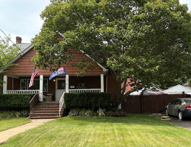 bungalow with covered porch, fence, and a front lawn