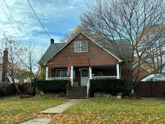 bungalow-style house featuring a porch, a front lawn, and fence