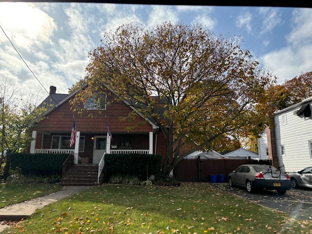 view of front facade with a porch, a front yard, and fence