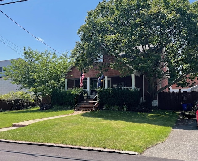 view of front of house featuring a front lawn, a porch, and fence