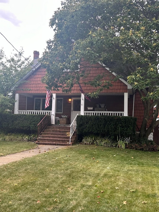 view of front of house featuring a porch, a chimney, and a front yard