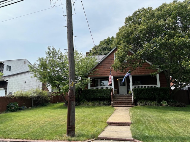 view of front facade featuring covered porch, a front lawn, and fence