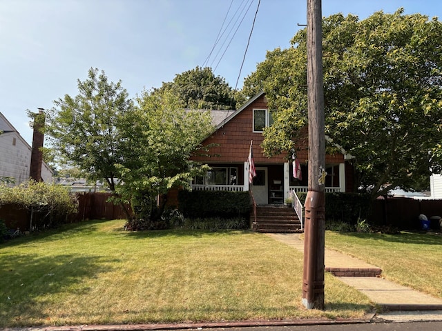 view of front of house featuring covered porch, a front lawn, and fence