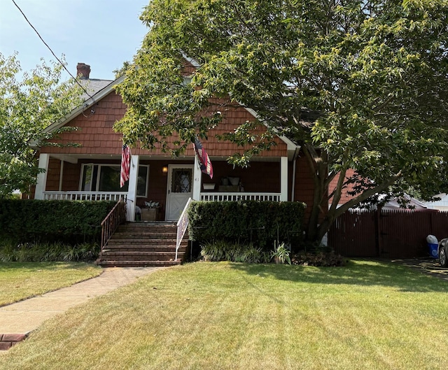 view of front facade with a porch, a front yard, and fence