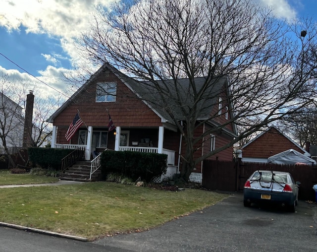 view of front of house featuring a front yard, covered porch, and fence