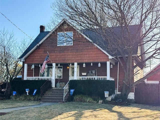 bungalow-style home featuring covered porch, a chimney, and a front yard