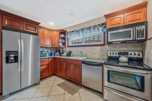 kitchen featuring appliances with stainless steel finishes, a sink, light stone counters, and decorative backsplash