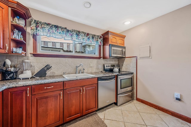 kitchen featuring decorative backsplash, appliances with stainless steel finishes, light tile patterned flooring, a sink, and baseboards