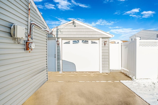 garage featuring concrete driveway and fence