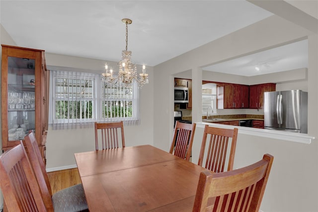 dining room featuring baseboards, an inviting chandelier, and light wood-style floors