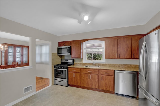 kitchen featuring stainless steel appliances, a sink, visible vents, light countertops, and brown cabinetry