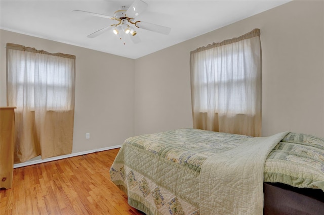 bedroom with a ceiling fan, baseboards, and wood finished floors