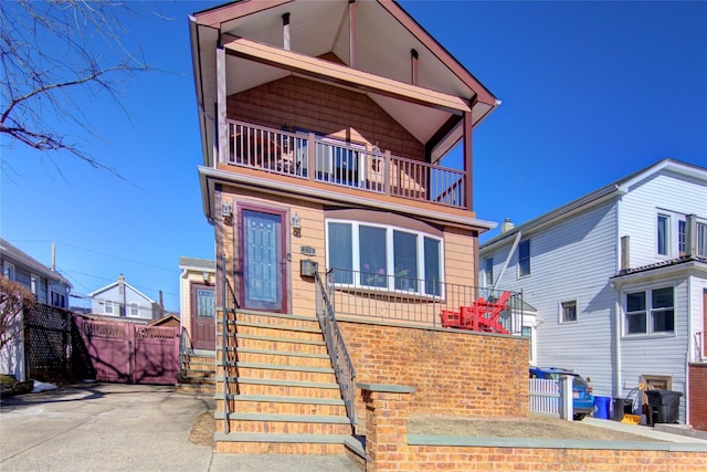 view of front of house featuring a balcony and fence