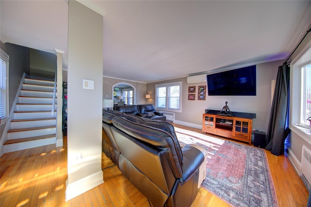 living area featuring arched walkways, hardwood / wood-style floors, stairs, and crown molding