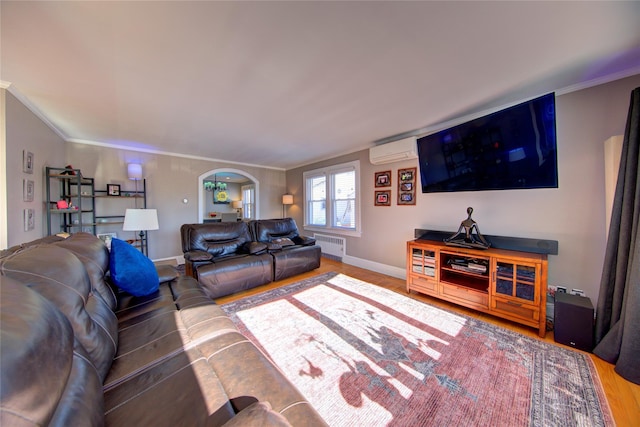 living area featuring arched walkways, wood finished floors, an AC wall unit, ornamental molding, and radiator