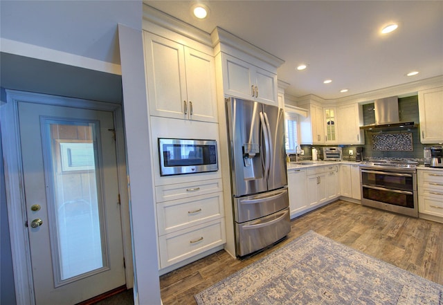 kitchen featuring wall chimney exhaust hood, appliances with stainless steel finishes, white cabinets, and dark wood-style flooring