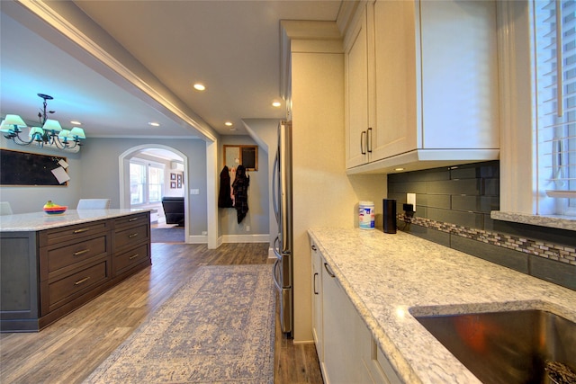 kitchen featuring tasteful backsplash, baseboards, arched walkways, ornamental molding, and dark wood-type flooring