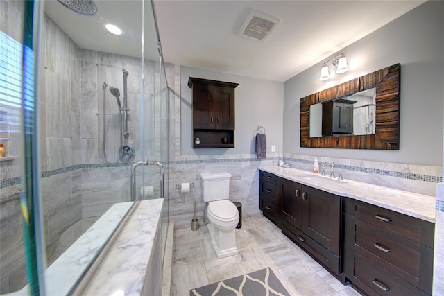 full bathroom with toilet, vanity, visible vents, tile walls, and a shower stall