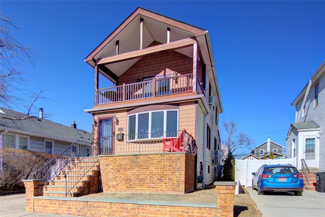 view of front of house with a balcony, stairs, and brick siding