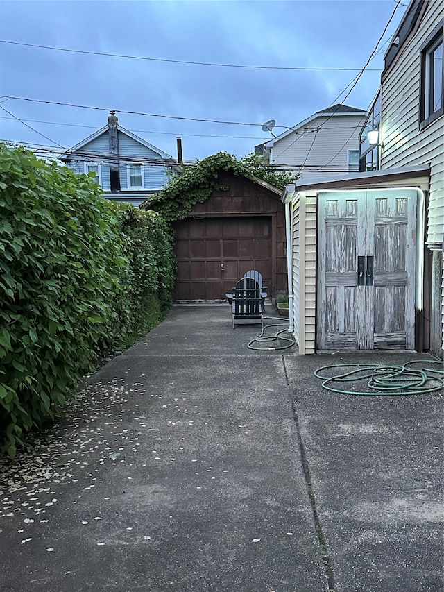 view of patio featuring a garage, driveway, and an outbuilding