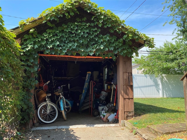 view of outbuilding with a garage, fence, and an outdoor structure