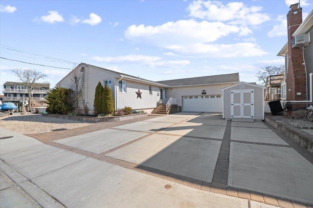 view of front of house with an attached garage, a storage shed, concrete driveway, and an outdoor structure