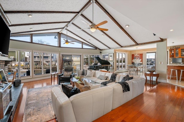 living room with beam ceiling, a fireplace, a ceiling fan, high vaulted ceiling, and hardwood / wood-style floors