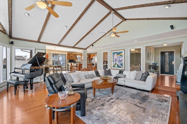 living area with a ceiling fan, wood finished floors, a textured ceiling, high vaulted ceiling, and beam ceiling