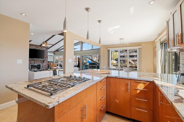 kitchen featuring light tile patterned floors, a fireplace, a ceiling fan, light stone countertops, and stainless steel gas stovetop