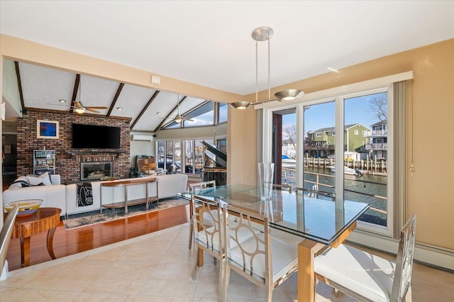 tiled dining room featuring lofted ceiling with beams, a brick fireplace, and ceiling fan