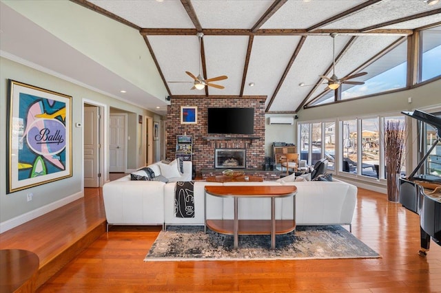 living room with ceiling fan, a fireplace, wood finished floors, and beam ceiling