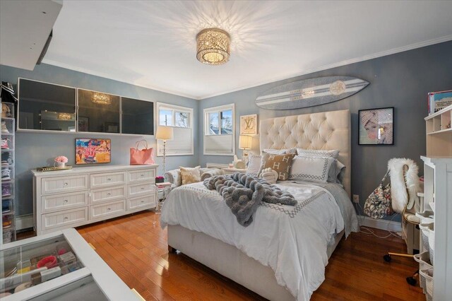 bedroom with baseboards, crown molding, and hardwood / wood-style floors