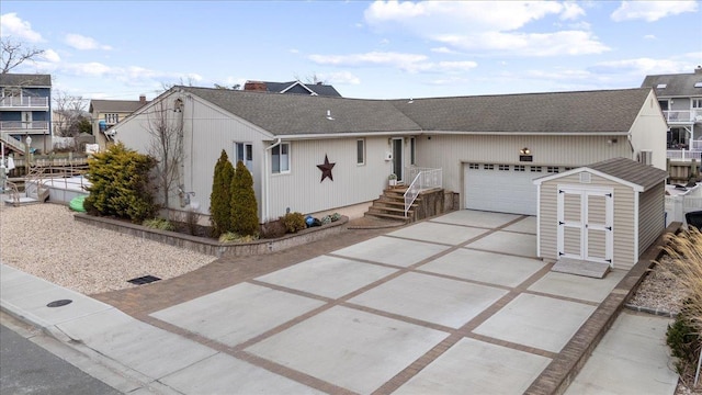 ranch-style home featuring an attached garage, a shingled roof, an outdoor structure, fence, and concrete driveway