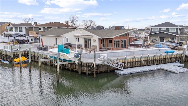 view of dock with a residential view, a water view, and fence