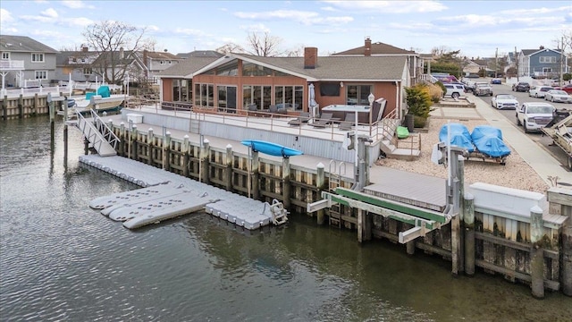 view of dock with a water view, boat lift, and a residential view