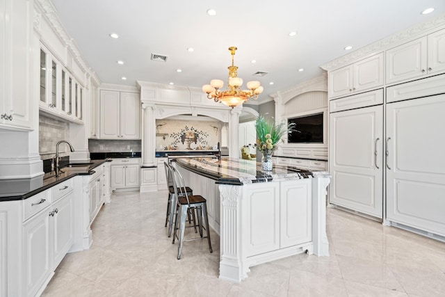 28 Whitney Cir, Glen Cove, NY 11542 - kitchen featuring visible vents, a sink, a notable chandelier, white cabinets, and a kitchen island with sink